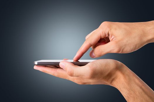 Hand hlding and touching smart phone with blank screen, side view on dark background.