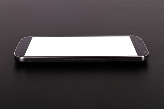 Smart phone with blank, white screen, side view on wooden table.
