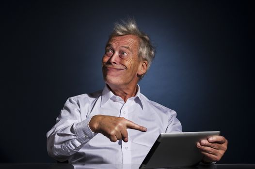 Senior businessman grinning with a look of fatuous self-satisfaction and pointing to his tablet computer with his finger as though indicating a great personal achievement, comic studio portrait