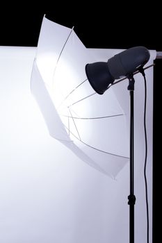 Empty photo studio with white background and lighting on dark.