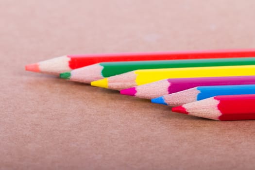 Colorful pencils in a row on textured background.