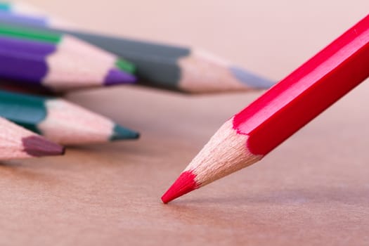 Colorful pencils on textured background, focused on red pencil.