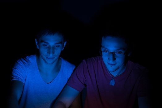 Two male friends online concentrating on the computer screen