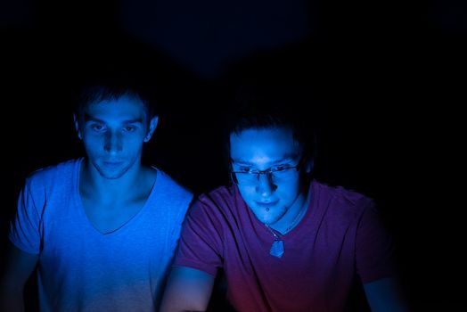 Two male friends online concentrating on the computer screen