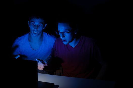 Two guys excited watching a laptop screen, a concept