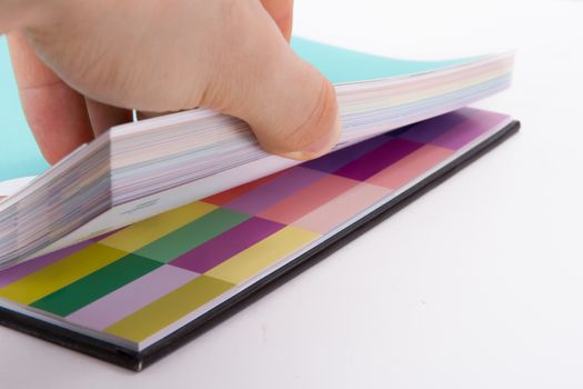 Hand holding sheets of color art book for page turn, isolated on white background.