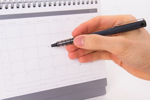 Hand holding pen and pointing a day of year 2013 desk calendar, isolated on white background.