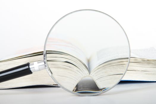 Magnifying glass and open dictionary book, isolated on white background.