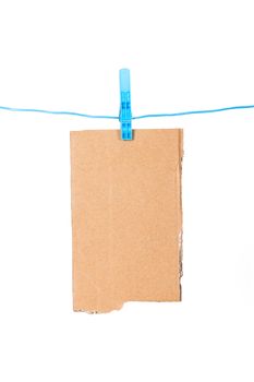 Teared, ripped cardboard with blue, plastic clothespin on nylon rope, isolated on white background.