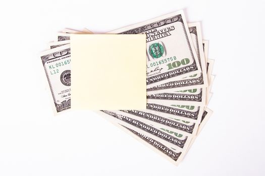 One hundred dollar bills with yellow, blank, empty sticky post it note for your message, isolated on white background.