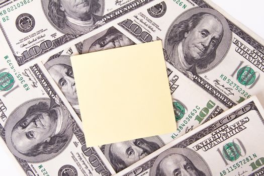 One hundred dollar bills with yellow, blank, empty sticky post it note for your message, isolated on white background.