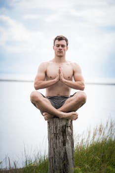 Young Adult Doing the Sukhasana (Easy position) in Yoga on a Stump in Nature