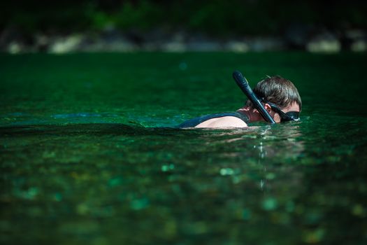 Young Adult Snorkeling in a river with Goggles and Scuba.