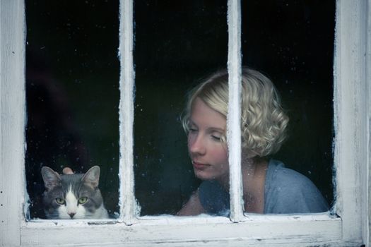 Woman and Cat Looking at the Rainy Weather By the Window Frame