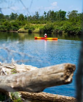 Young Woman Kayaking Alone on a Calm River and Wearing a Safety Vest