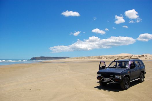 Car at white sand beach, New Zealand