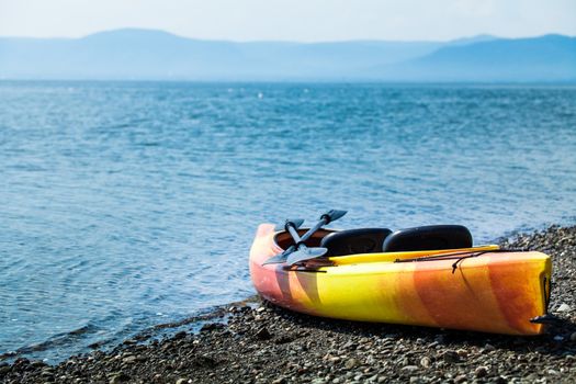 Orange and Yellow Kayak With Oars on the Sea Shore During a beautiful Day of Summer