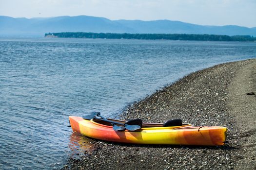 Orange and Yellow Kayak With Oars on the Sea Shore During a beautiful Day of Summer