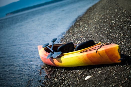 Orange and Yellow Kayak With Oars on the Sea Shore During a beautiful Day of Summer