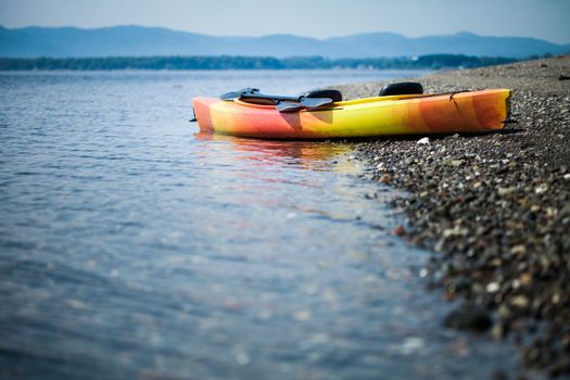 Orange and Yellow Kayak With Oars on the Sea Shore During a beautiful Day of Summer