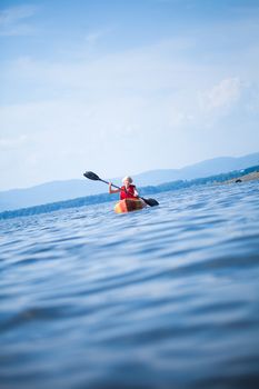 Young Woman Kayaking Alone on a Calm Sea and Wearing a Safety Vest