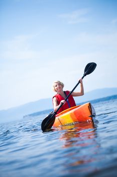 Young Woman Kayaking Alone on a Calm Sea and Wearing a Safety Vest