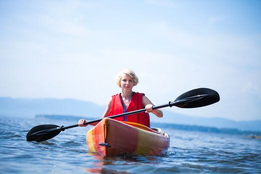 Young Woman Kayaking Alone on a Calm Sea and Wearing a Safety Vest