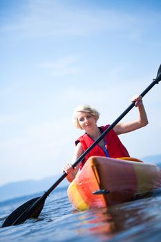 Young Woman Kayaking Alone on a Calm Sea and Wearing a Safety Vest