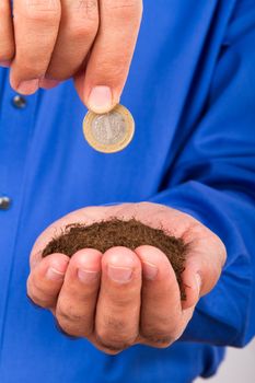 Businessman hand holding pile of soil and coin for growing finance.