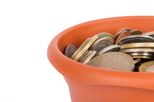 Detail view of flower pot and full of coins money inside, isolated on white background.