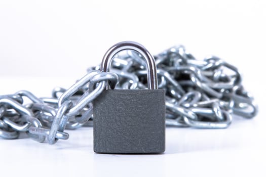 Heap of metal chain with security lock, isolated on white background.