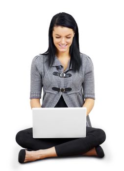 Pretty young brunette woman or student looking down at laptop on folded legs on white