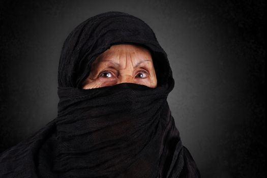 Dramatic portrait of senior muslim woman with niqab and hijab