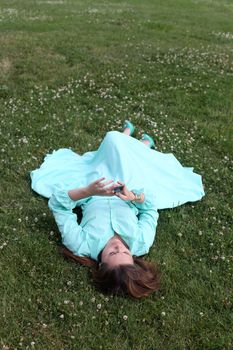 Young woman lying on the grass with phone in hand