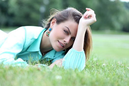 Portrait of young woman lying on a green lawn