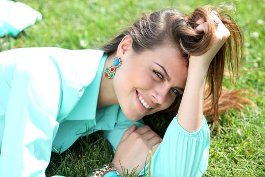 Portrait of young woman lying on a green lawn