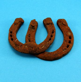 retro rusty pair of upturn horse shoes on blue background.