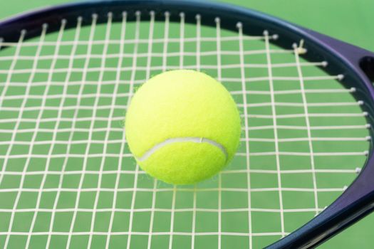Tennis racket with ball over green hard surface court
