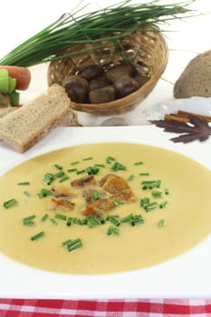 a plate of sweet chestnut soup with roasted chestnuts and chives