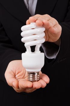 Business woman shows and holds economical lightbulb.