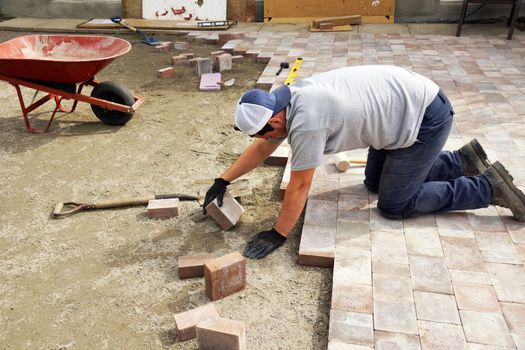 Young man laying down paver as part of landscaping