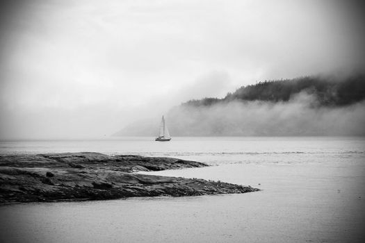 Romantic landscape: sailboat in the fog in dramatic  black and white