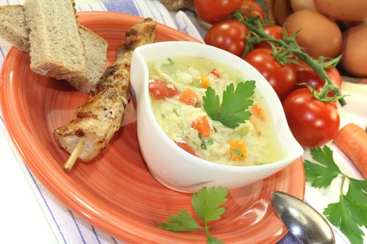 Chicken soup with eggs, noodles and greens on bright background