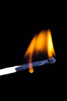 Burning match with flame on black background.