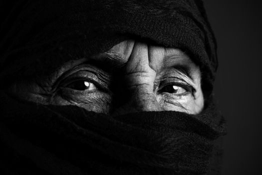 Eyes of senior muslim woman with niqab, looking at camera, black and white