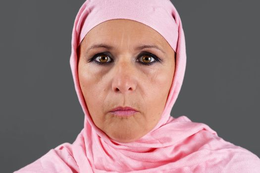 Portrait of serious middle aged muslim woman with pink scarf or hijab