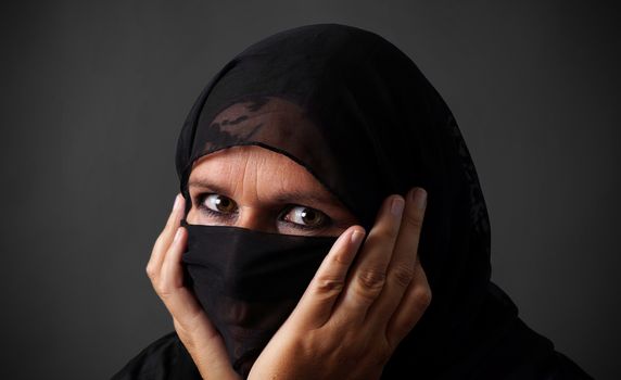 Middle-aged muslim woman hiding her face looking angry