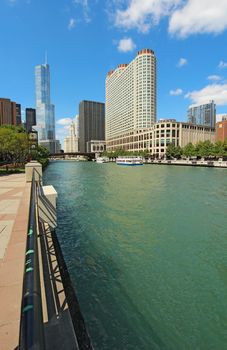Tour boats and the city skyline along the Chicago River in Chicago, Illinois against a bright blue sky with white clouds