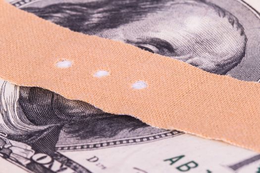 Adhesive bandage, plaster on one hundred dollar bill.