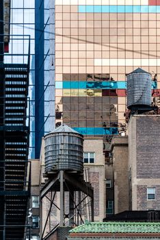 Typical New York facades with reflections on glass, old wooden water tower and fire ladders in New York